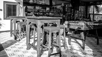 Zona de bar con taburetes de madera y una barra, rodeada de estantes llenos de botellas.