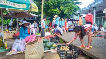A bustling outdoor market with people shopping and vendors selling goods.