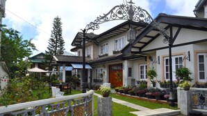 A traditional house with a front porch, a small garden, and a decorative iron gate. - Cocoon Hills (Nuwara Eliya)