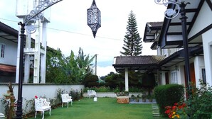 A well-maintained garden with a decorative metal archway, a lawn, and potted plants. - Cocoon Hills (Nuwara Eliya)