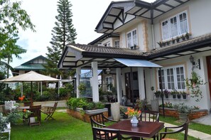 A two-story house with a covered patio, outdoor seating, and a garden. - Cocoon Hills (Nuwara Eliya)
