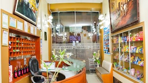 A hotel reception area with a counter, seating, a glass display case with snacks, and a framed painting on the wall. - Colon Plaza Hotel (Ica)