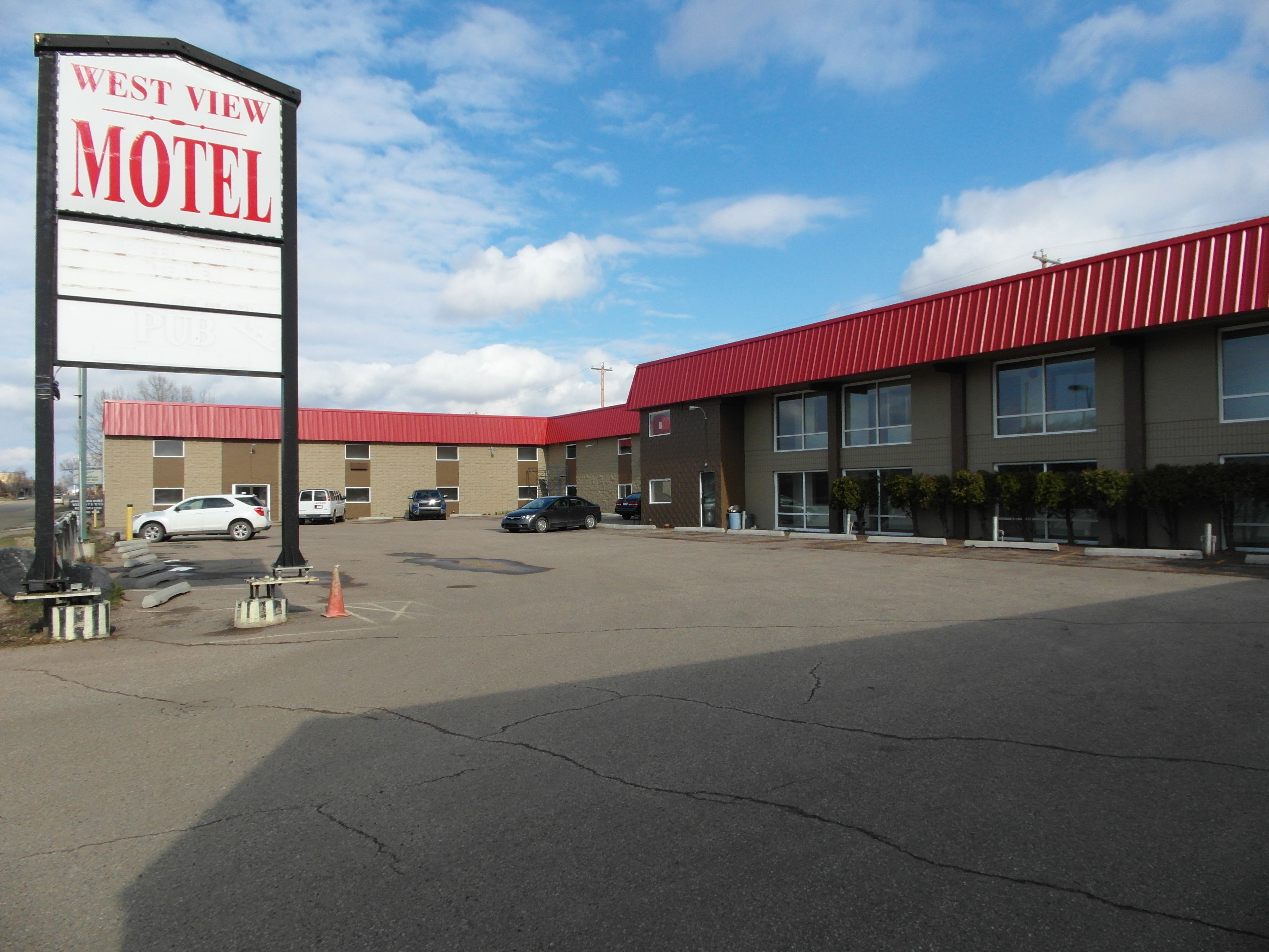 A motel with a red roof and multiple parking spaces.