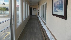 A hallway with large windows, a radiator, and a framed picture on the wall. - West View Motel (Hanna)