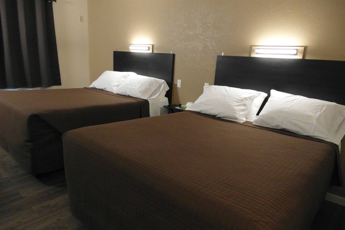 Ett hotellrum med två separata sängar, var och en med en sänggavel och ett nattduksbord.