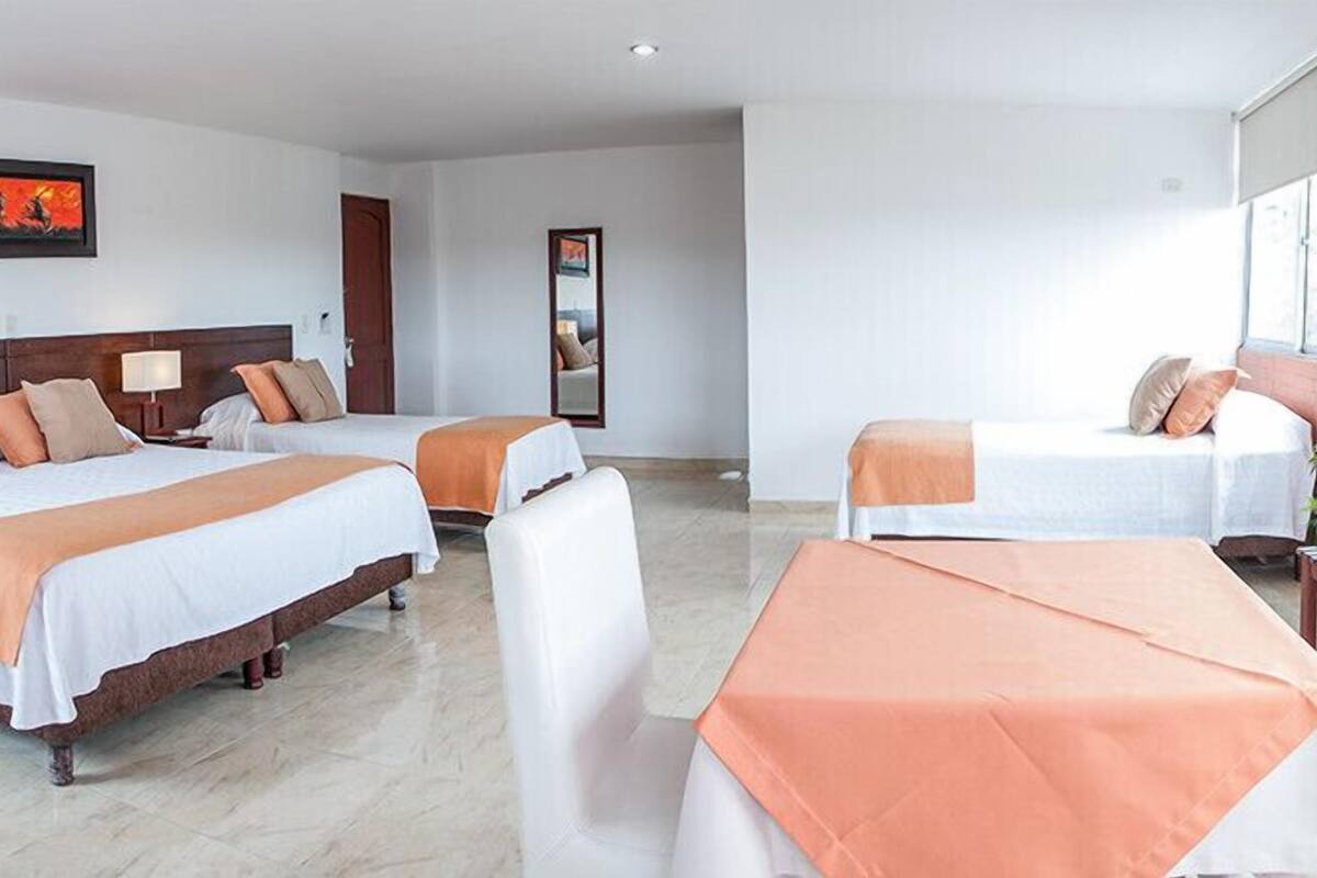 A hotel room with two beds, a sitting area, and a large window.