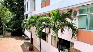 A building with a white facade, multiple windows, and a paved walkway. - Hotel Hacaritama Colonial (Villavicencio)