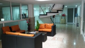 A modern living room with a sofa, coffee table, and a staircase. - Hotel Napolitano (Villavicencio)