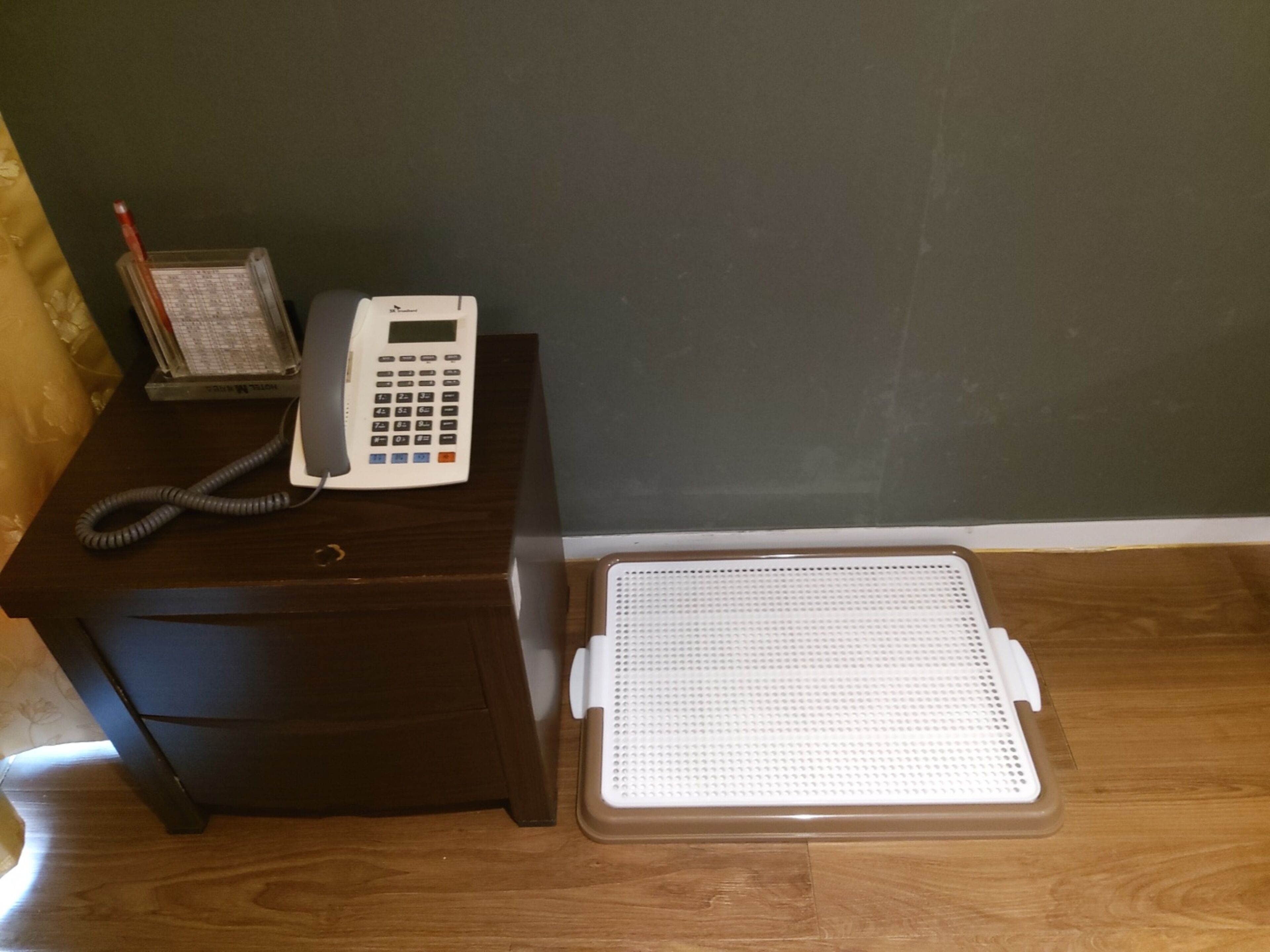 A wooden nightstand with a telephone, a small book, and a decorative item.