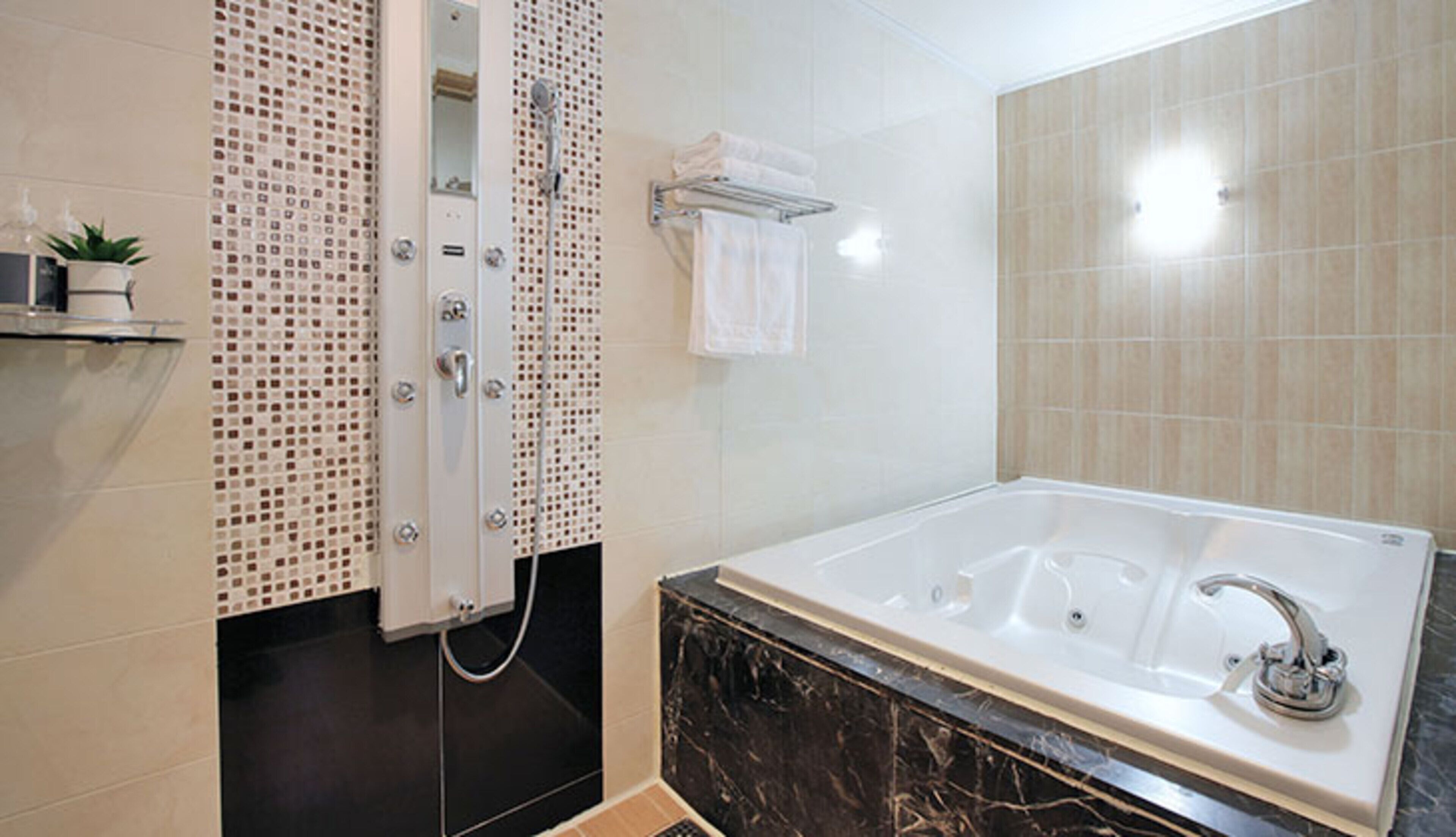 A modern bathroom with a large bathtub, a shower enclosure, and a tiled wall.
