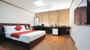 Una habitación de hotel con cama, escritorio y una pequeña kitchenette.