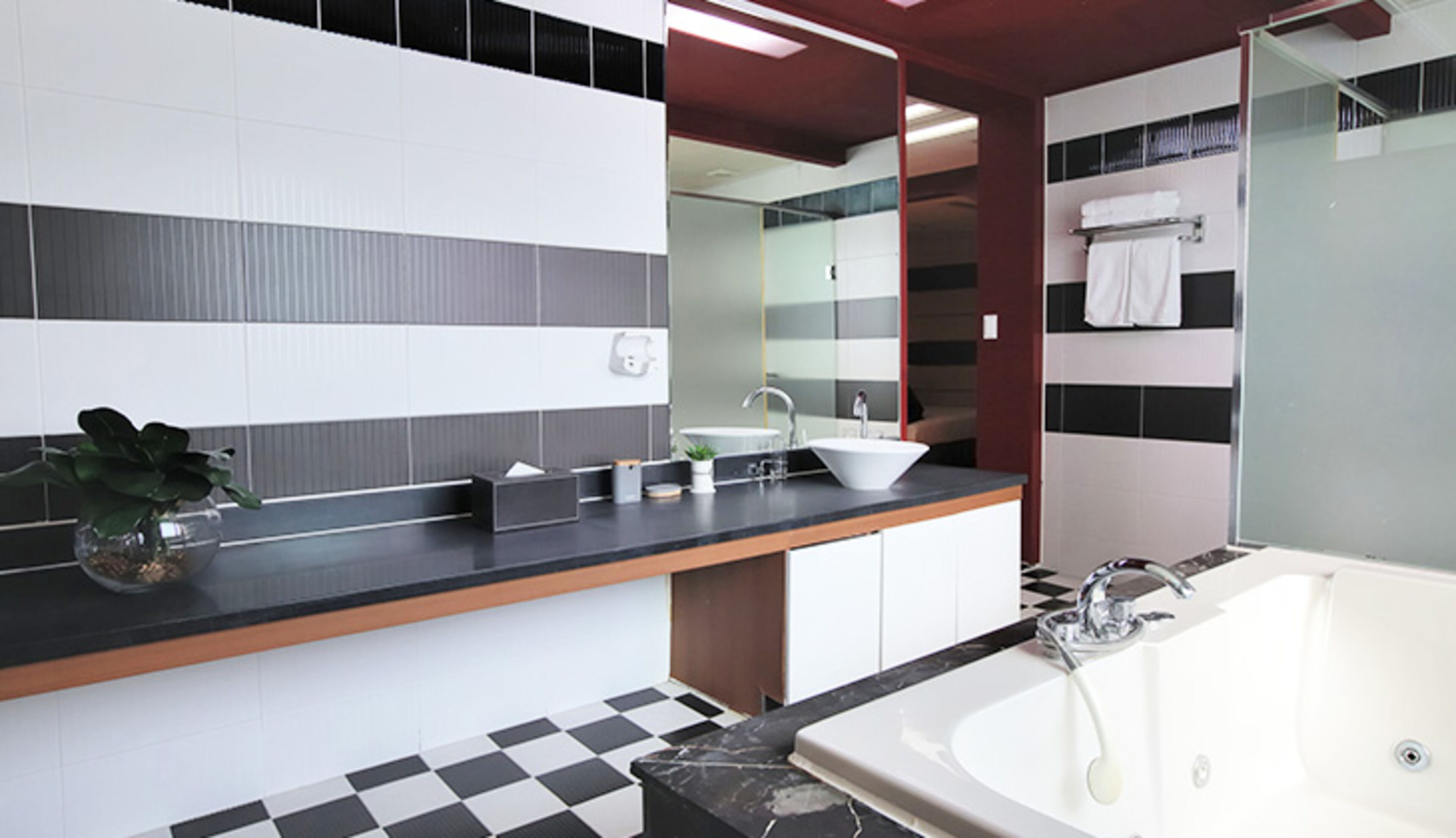 Une salle de bain moderne avec un sol à carreaux noirs et blancs, un lavabo blanc et un grand miroir.