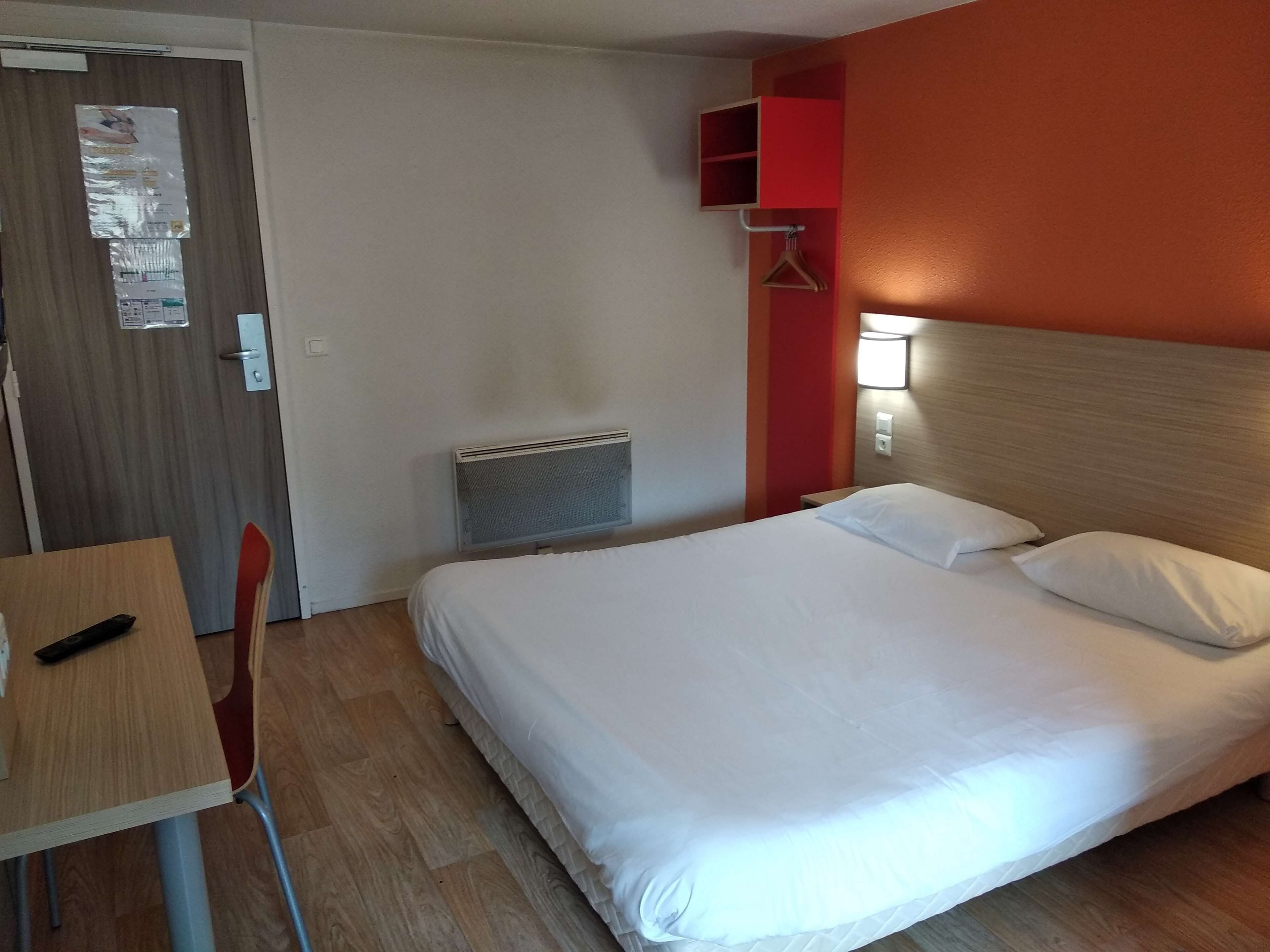 A hotel room with a bed, a desk, and a chair.