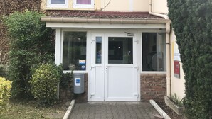 Een gebouw met een witte deur, twee ramen en een klein portaal.