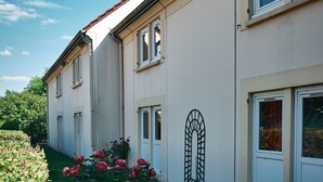 Een gebouw met een witte gevel, meerdere ramen en een rood dak.