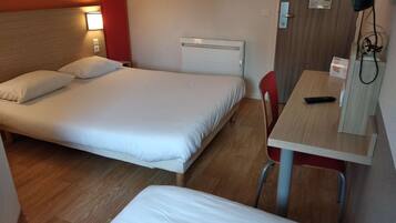 Quarto de hotel com duas camas, uma escrivaninha e uma cadeira.
