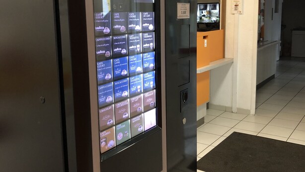 Een digitaal menubord toont verschillende koffieopties in een moderne inrichting.