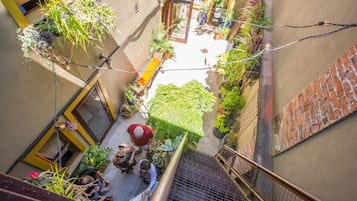 Un patio estrecho con plantas en macetas, un pequeño espacio para sentarse y una escalera que lleva a un nivel superior.
