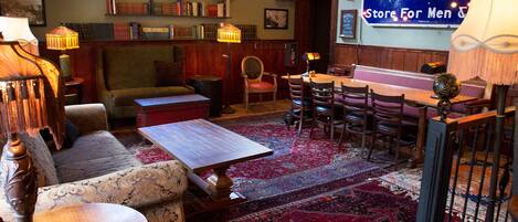 A cozy inn with a bar area, a billiards table, and a large rug.