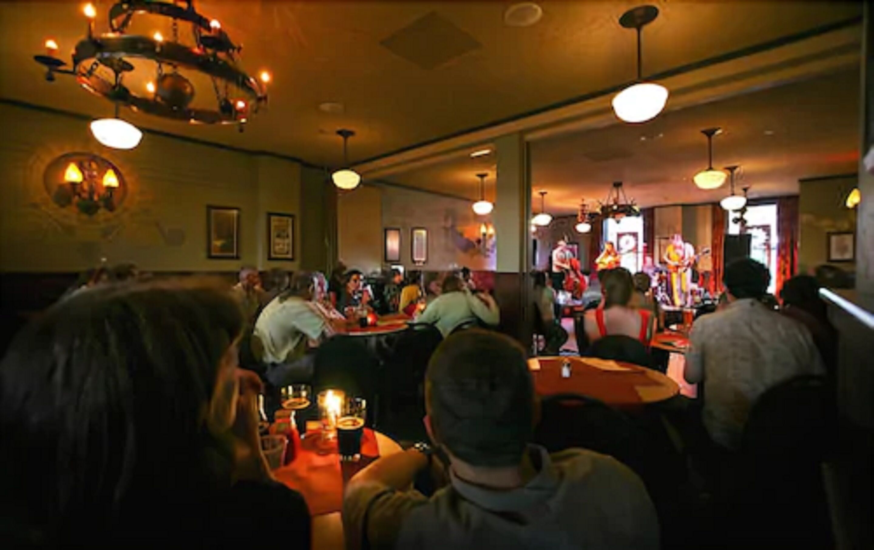 A restaurant with tables and chairs, a band performing, and a warm ambiance.