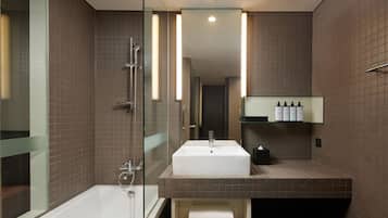 A modern bathroom with a glass shower enclosure, a white sink, and a built-in towel rack.