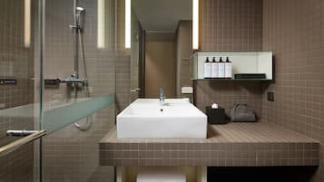 Un baño moderno con un lavamanos grande de color blanco, una cabina de ducha de vidrio y un perchero para toallas.