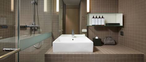 Un baño moderno con un lavamanos grande de color blanco, una cabina de ducha de vidrio y un perchero para toallas.