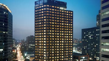 A high-rise hotel with multiple floors and illuminated windows, surrounded by other buildings.