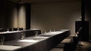 A conference room with a long table, chairs, a podium, and a projector screen.