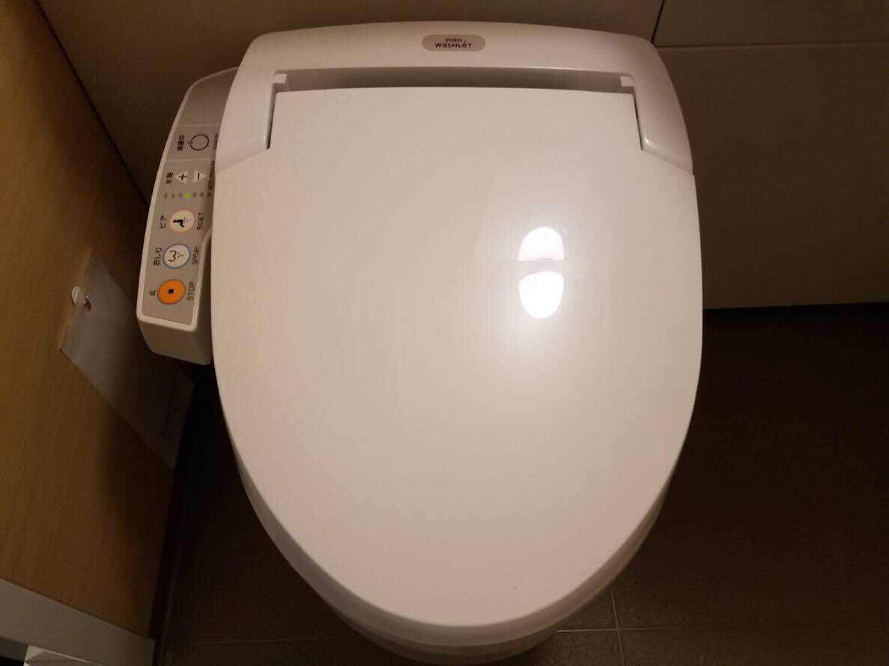 Un inodoro blanco con un panel de control que incluye botones y una pantalla.