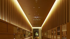 A long, narrow hallway with wooden paneling on both sides and a tiled floor. - Candeo Hotels Matsuyama Okaido (Matsuyama)