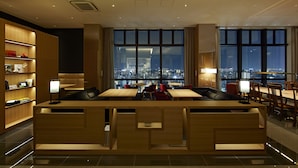 A modern hotel lobby with a reception desk, seating area, and large windows offering a city view. - Candeo Hotels Matsuyama Okaido (Matsuyama)