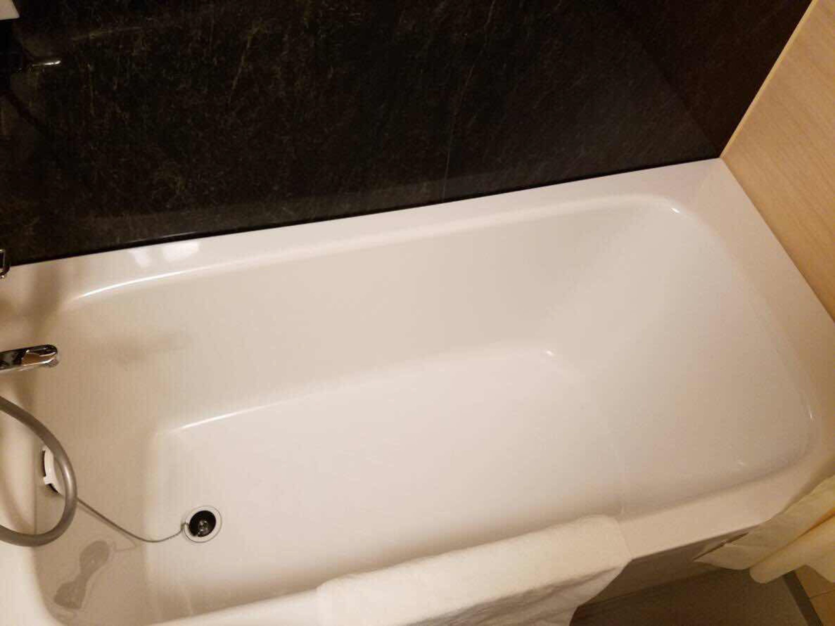 Une baignoire blanche dans une salle de bain avec un comptoir noir.