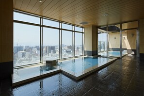 Piscina interior moderna com grandes janelas que oferecem vista para a cidade.