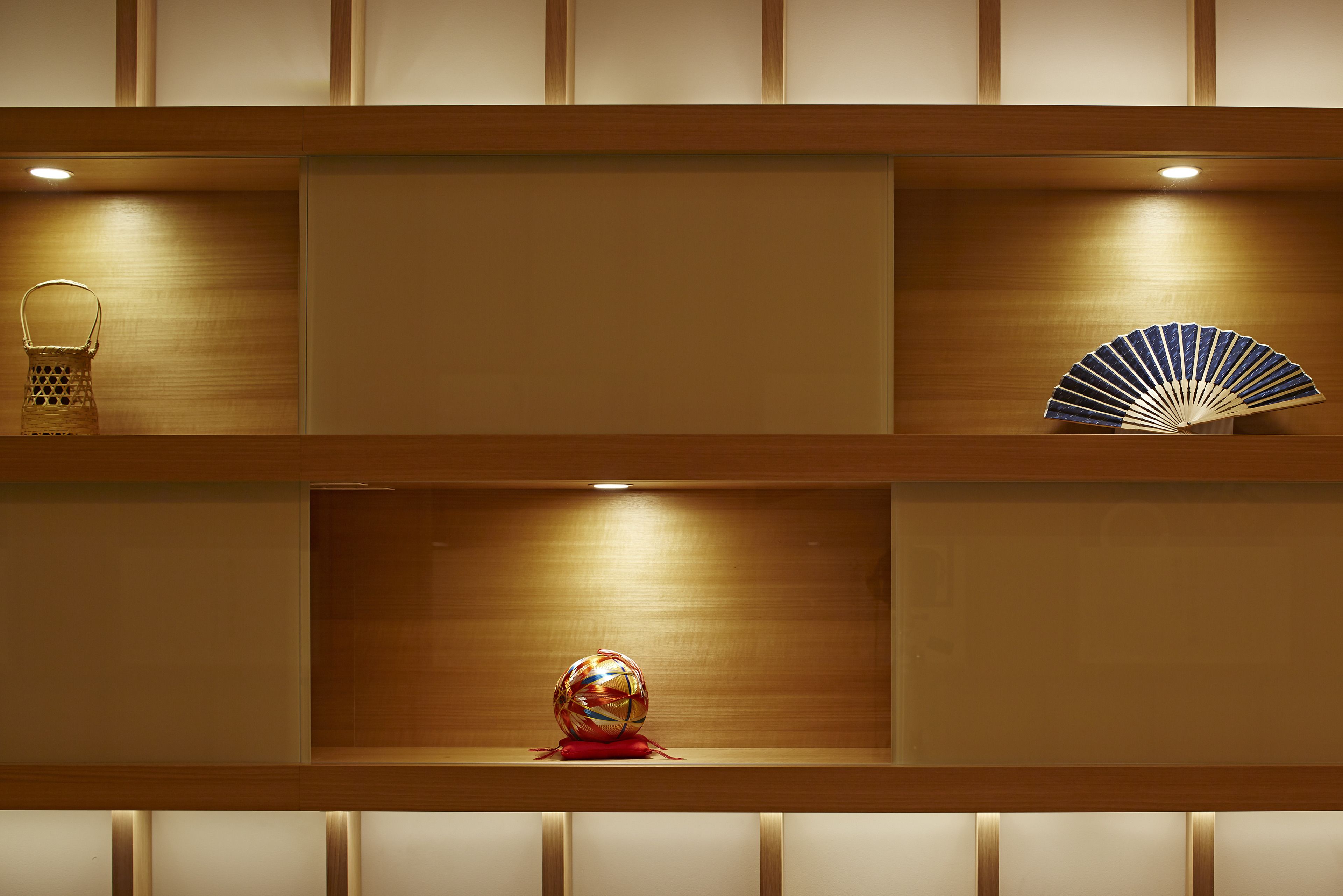 A wooden shelf with a basket, a decorative fan, and a colorful spherical object.