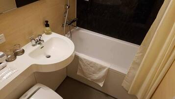 A bathroom with a sink, mirror, toilet, and bathtub.