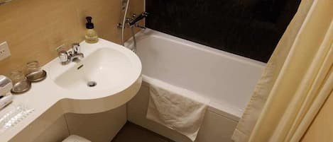 A bathroom with a sink, mirror, toilet, and bathtub.