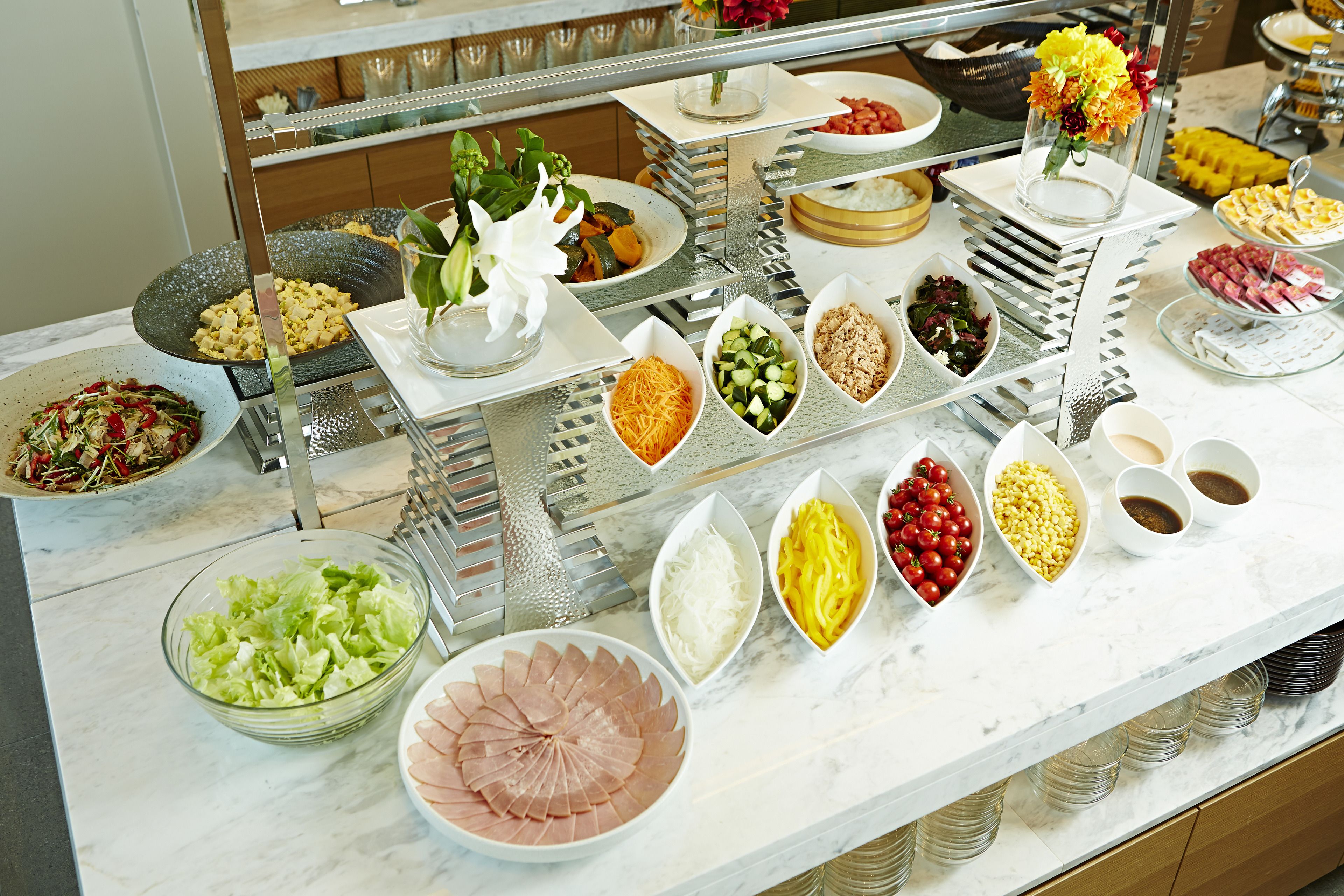 A buffet with various food items and a flower arrangement.