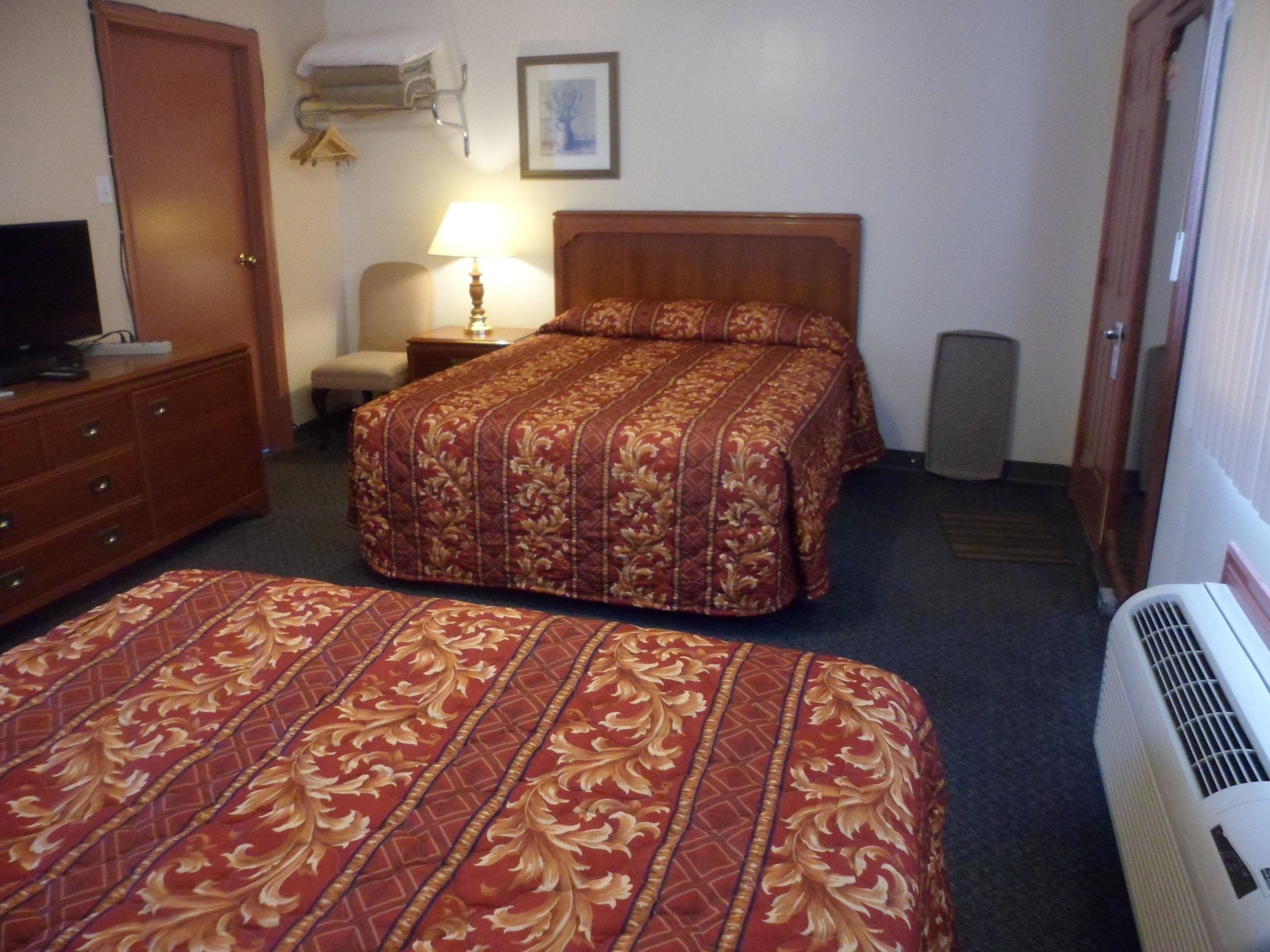 Habitación de hotel con dos camas, televisión, lámpara y calefacción.