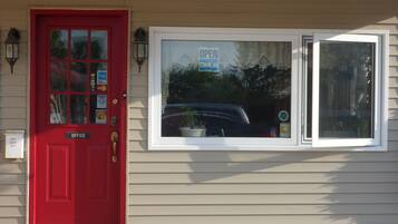 Una puerta roja con un cartel que dice 'Key Drop Off', un cartel que dice 'Come In' y una ventana con un cartel que dice 'Open'.