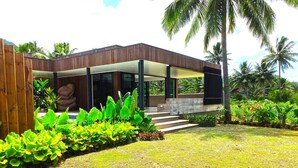 A modern house with a wooden deck, a stone pathway, and lush greenery. - Pacific Palms Luxury Villa (Rarotonga)