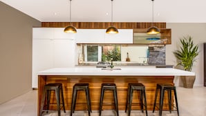 A modern kitchen with a large island, wooden accents, and pendant lighting. - Pacific Palms Luxury Villa (Rarotonga)