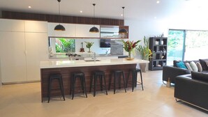 A modern kitchen with a central island, bar stools, and pendant lighting. - Pacific Palms Luxury Villa (Rarotonga)