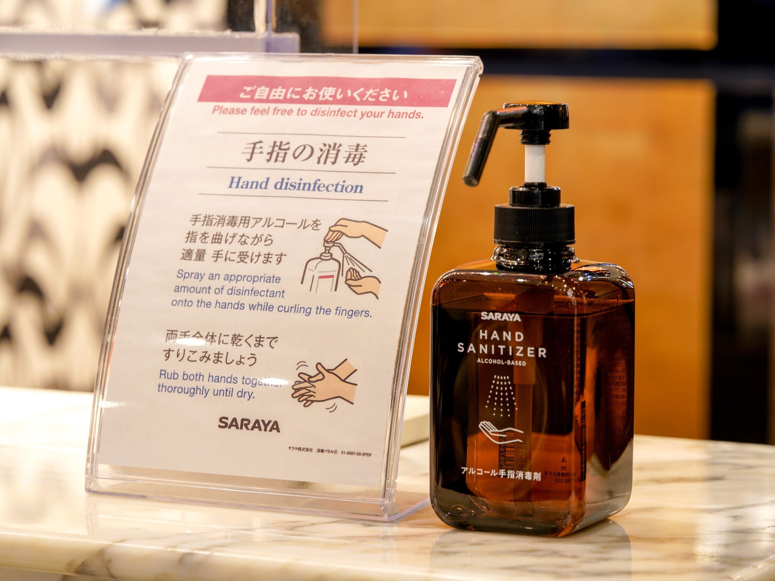 A hand sanitizer bottle and a sign instructing on hand disinfection.