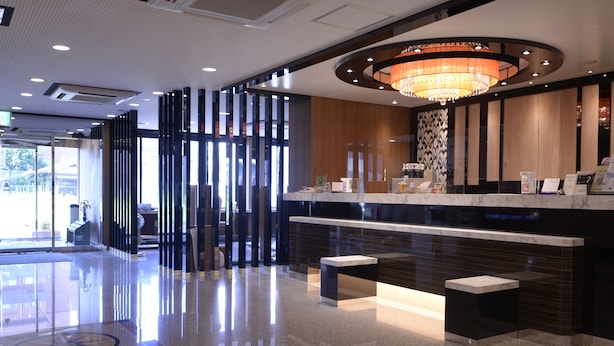 A modern hotel lobby with a reception desk, seating area, and a large chandelier. - APA Hotel Nishimaizuru-Ekimae (Maizuru)