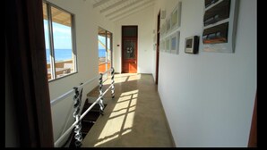 A hallway with a view of the ocean, a wooden door, and a staircase. - The Ocean Front (Colombo)