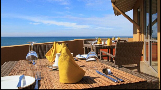 A dining area with tables set for two, overlooking the sea. - The Ocean Front (Colombo)