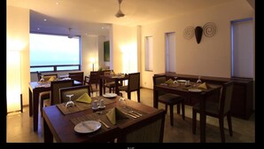 A dining area with multiple tables and chairs, equipped with table settings and a ceiling fan. - The Ocean Front (Colombo)