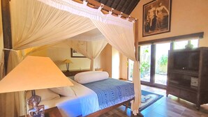 A room with a bed under a canopy, a lamp, a statue, and a painting on the wall. - Villa Plawa Asri (Seminyak)
