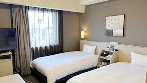 Habitación de hotel con dos camas, televisión, mesita de noche, lámpara y un cuadro en la pared.